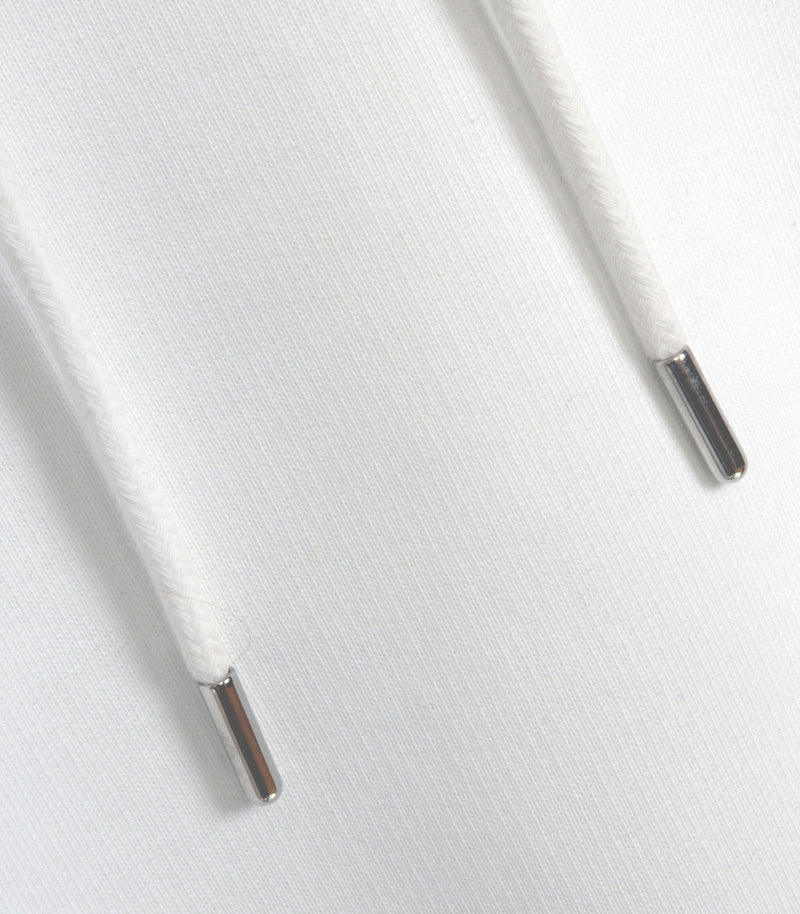 Close-up of white drawstrings with silver metal tips on a white fabric surface.