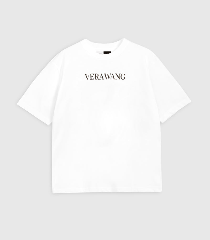 Flat lay product view of a relaxed, loose-fit white cotton t-shirt featuring the minimal 'VERA WANG' logo printed in black across the upper chest, complete with wide short sleeves, a classic crew neckline, and a visible split black-and-white inner neck label against a light grey background.