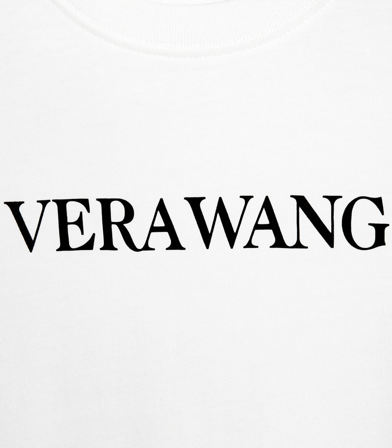 A high-contrast, close-up product shot focusing on the chest graphic of a white cotton t-shirt, showcasing the minimal 'VERA WANG' brand logo printed cleanly in black directly below a classic ribbed crew neck collar.