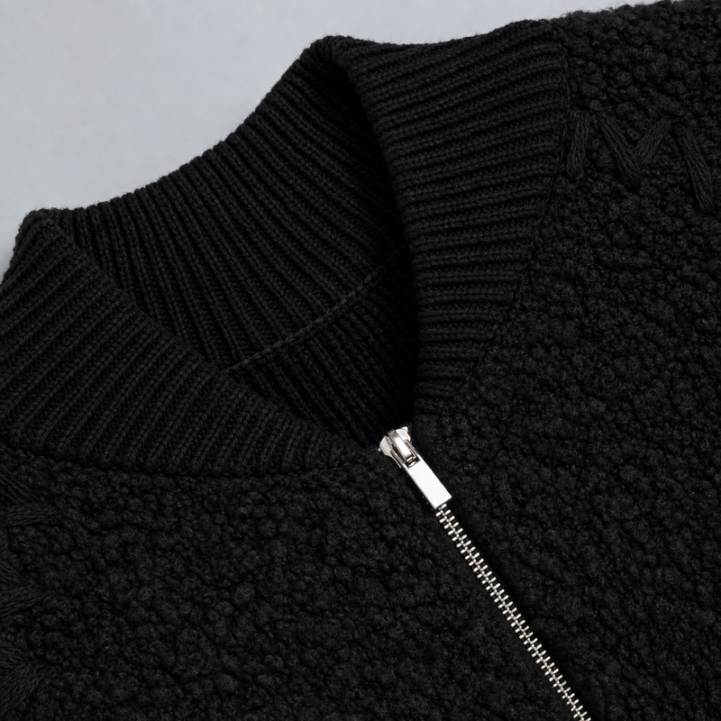 Close-up of a black textured fleece zip jacket with a ribbed knit collar and a silver zipper.