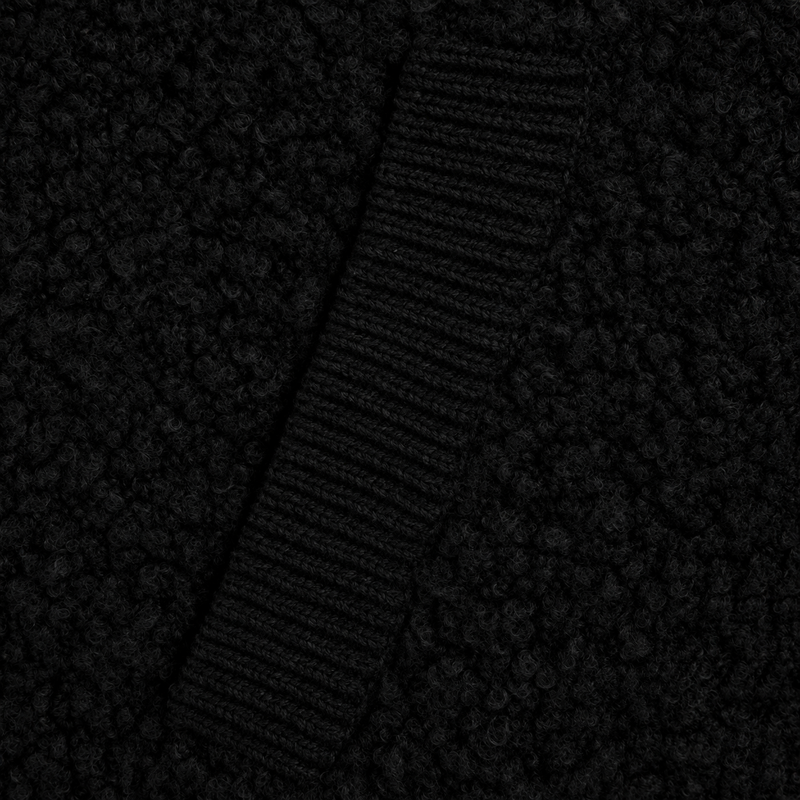 Close-up of a black textured fabric with a ribbed knit stripe running diagonally across the frame.