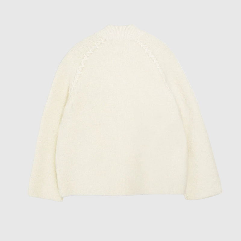An off-white fuzzy knit sweater shown from the back, featuring textured zigzag knit detailing along the upper back and raglan sleeves, set against a plain white background.