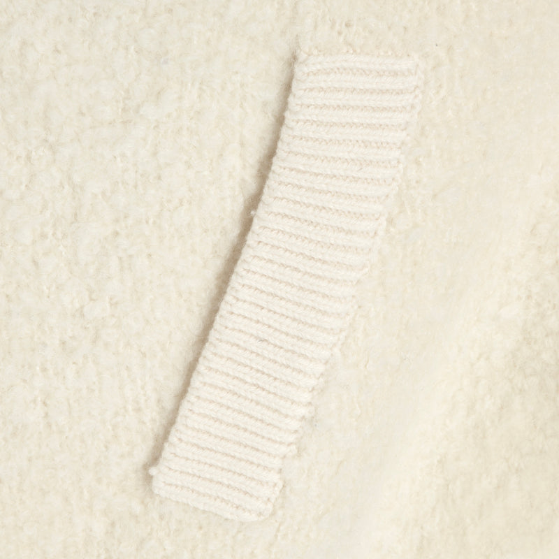Close-up of a ribbed knit trim detail on a cream-colored textured fabric.