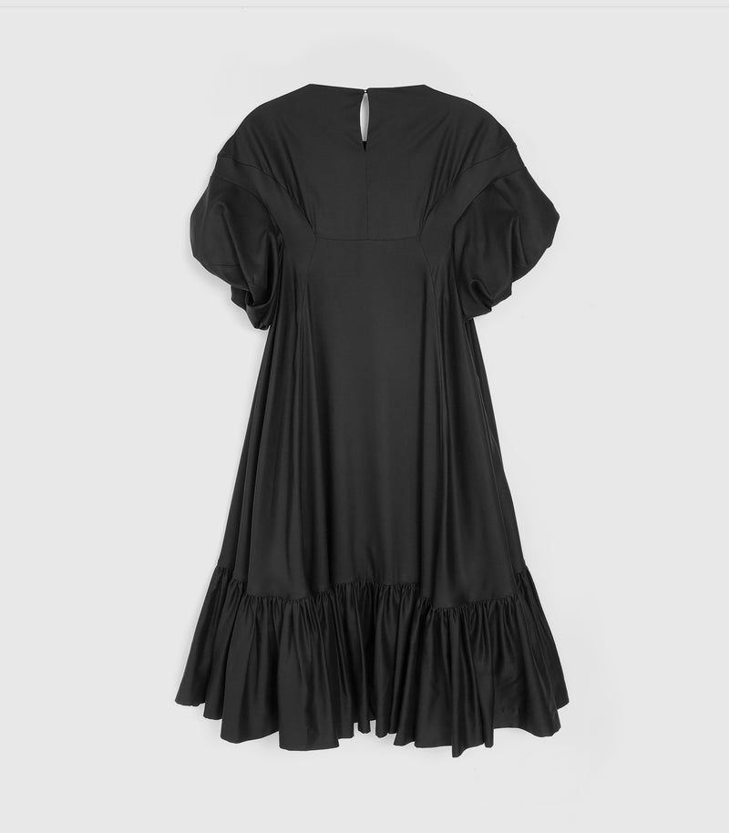 Flat-lay rear view of a knee-length black smock dress featuring a relaxed, voluminous silhouette, a high back neckline with a central keyhole cutout closure, and dramatic gathered ruffle short sleeves. The dress is constructed with a contoured back panel design and a heavily gathered tiered ruffle hemline, presented flat against a light grey background.