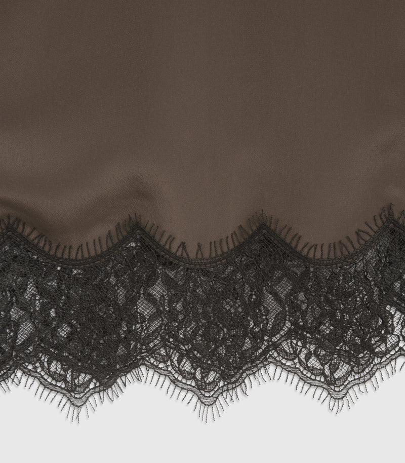 Close-up of a black sheer fabric with a scalloped floral lace trim along the bottom edge.