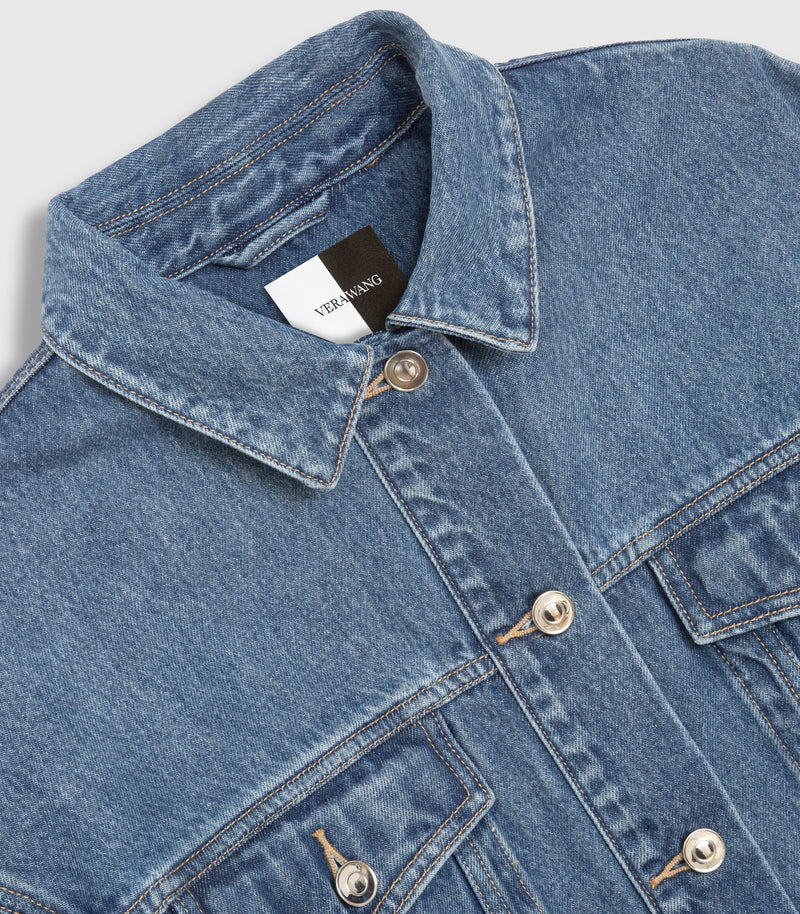 Close-up of a blue denim jacket with a pointed collar, silver-toned snap buttons, and a visible 