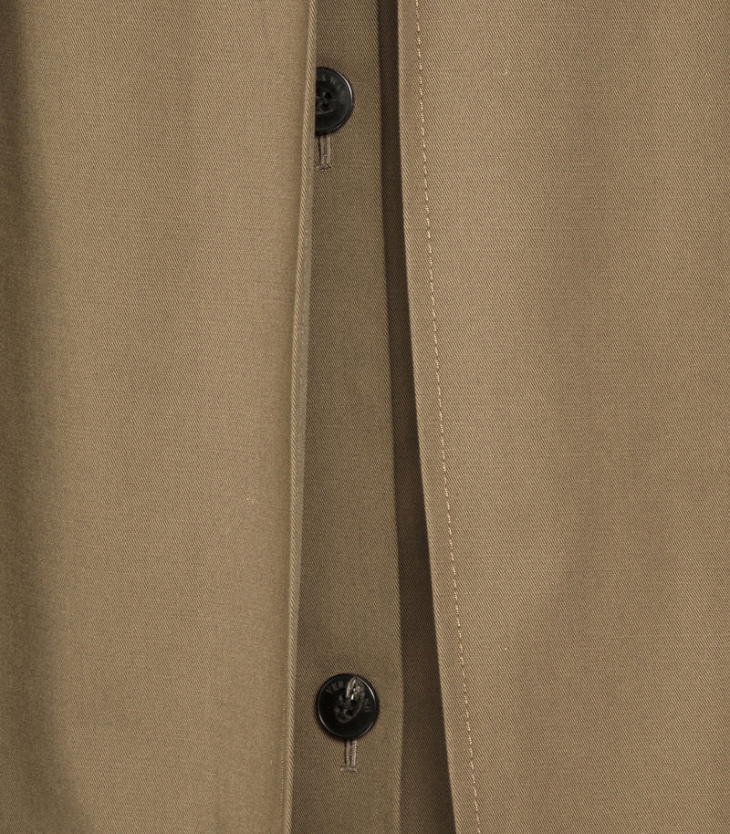Close-up of a tan or khaki fabric garment with black buttons and visible stitching along the front opening.