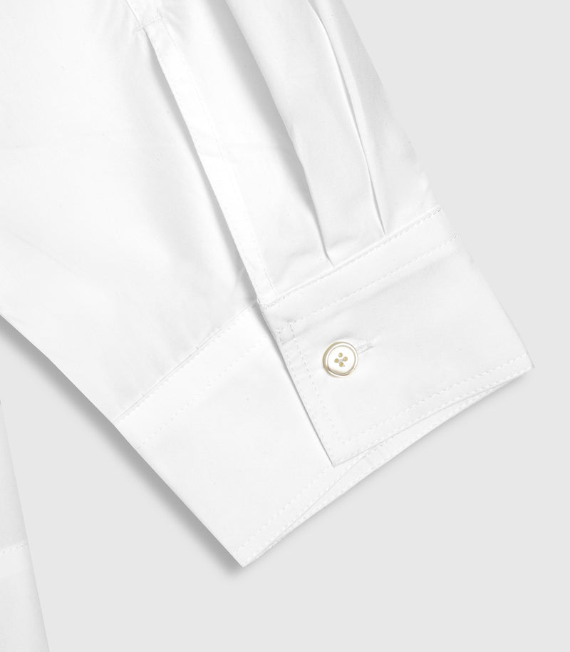 Close-up of a white long-sleeve dress shirt cuff with a single-button placket and a small cream-toned button, shown on a light gray background.