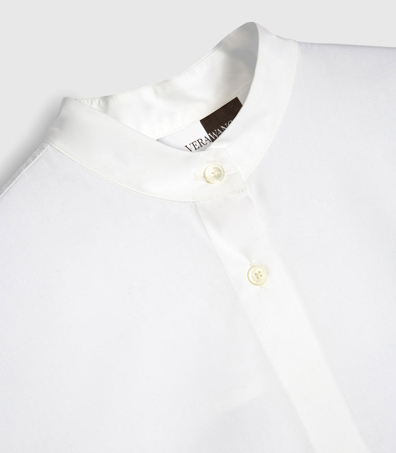 Close-up of a white button-front shirt with a stand collar and cream buttons, showing part of the neck label that reads 