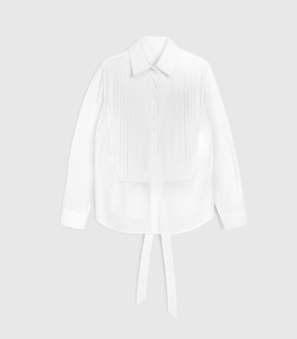 A white long-sleeve blouse with a pointed collar, front button placket, vertical pleat detailing on the chest, and a tie detail at the waist, shown against a light gray background.