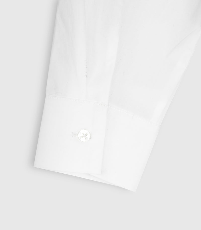 Close-up of a white long-sleeve dress shirt cuff with a single button closure, shown on a light gray background.