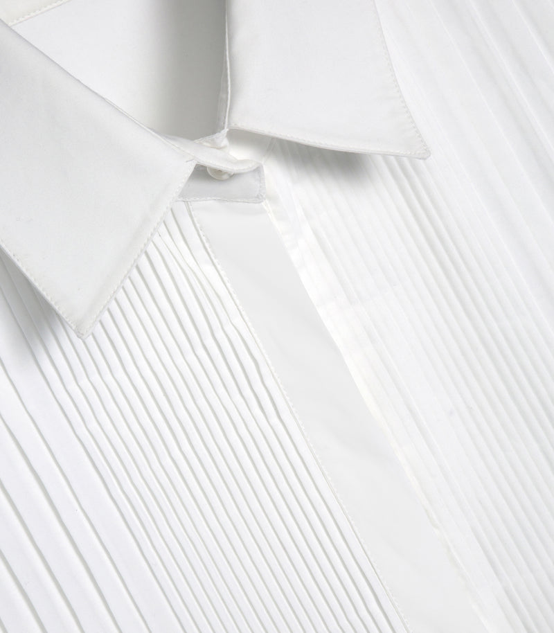 Close-up of a white pleated shirt with a pointed collar and front placket, showing the fabric texture and stitching.