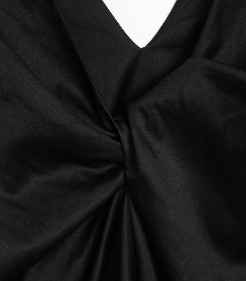 Close-up of a black satin or silky fabric with a V-neckline and gathered twist detail at the center.